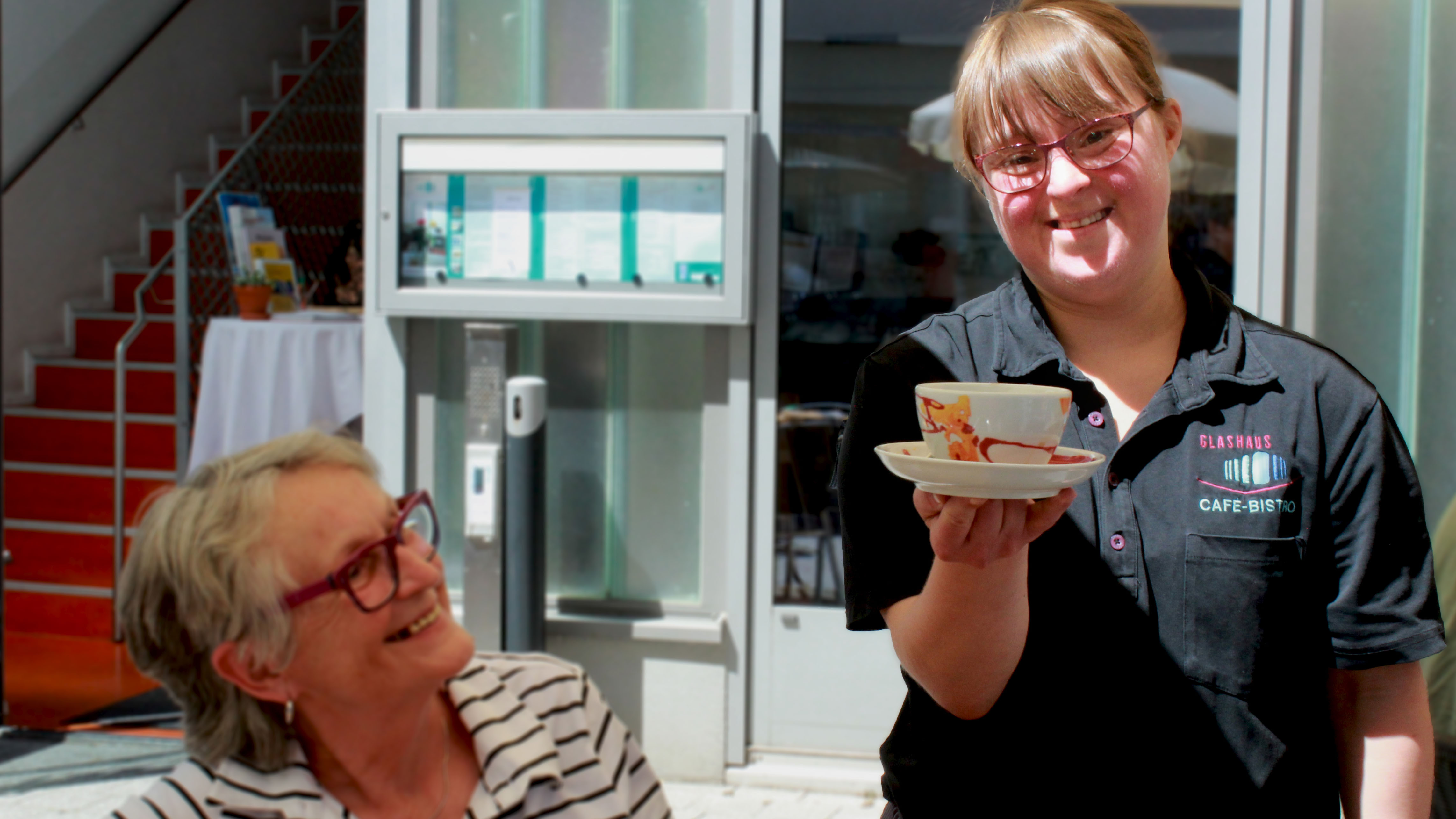 Junge Frau serviert einem Gast einen Kaffee